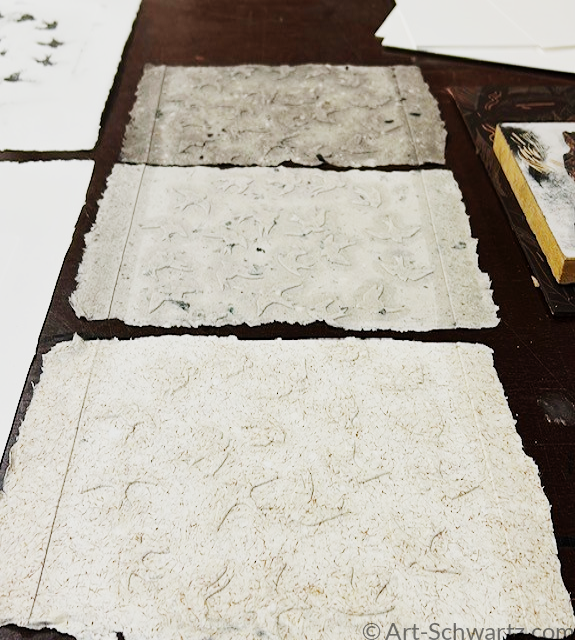 Drie zelfgemaakte vellen handgeschept papier op tafel