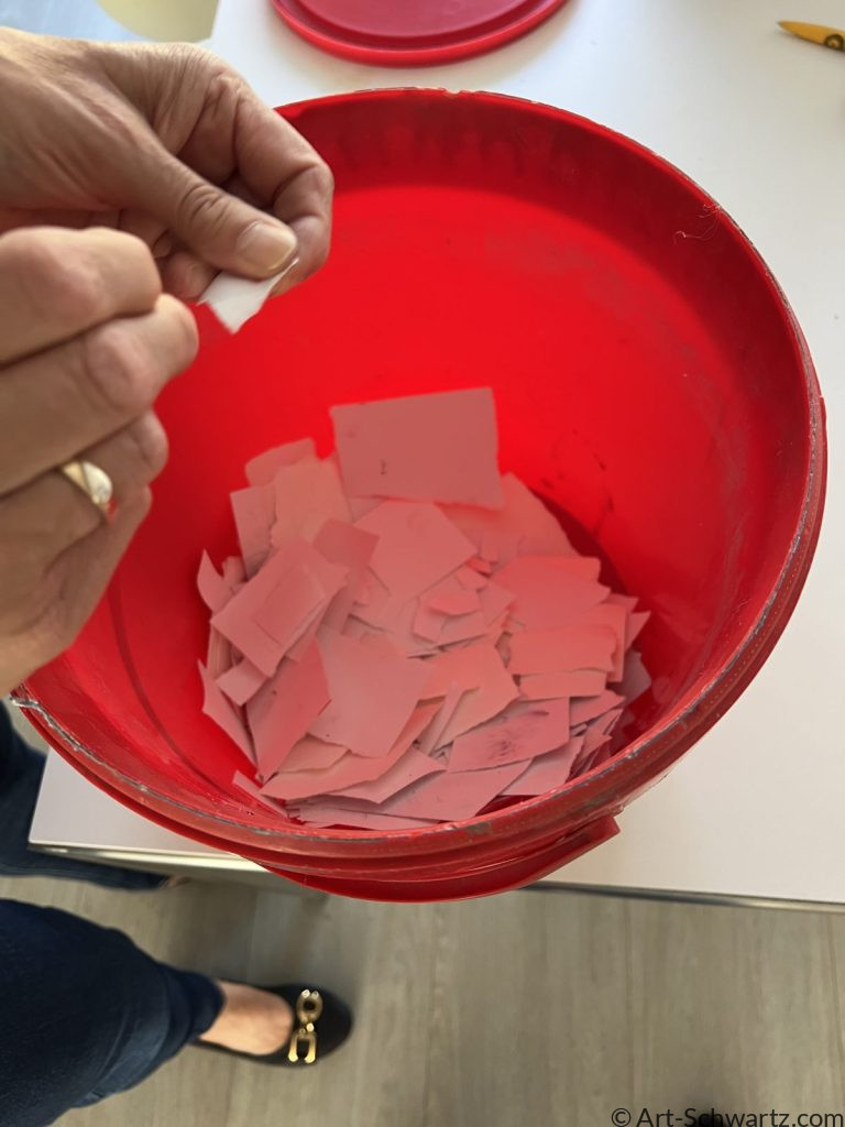 Roze papier scheuren in kleine stukjes als eerste stap voor het maken van papierpulp